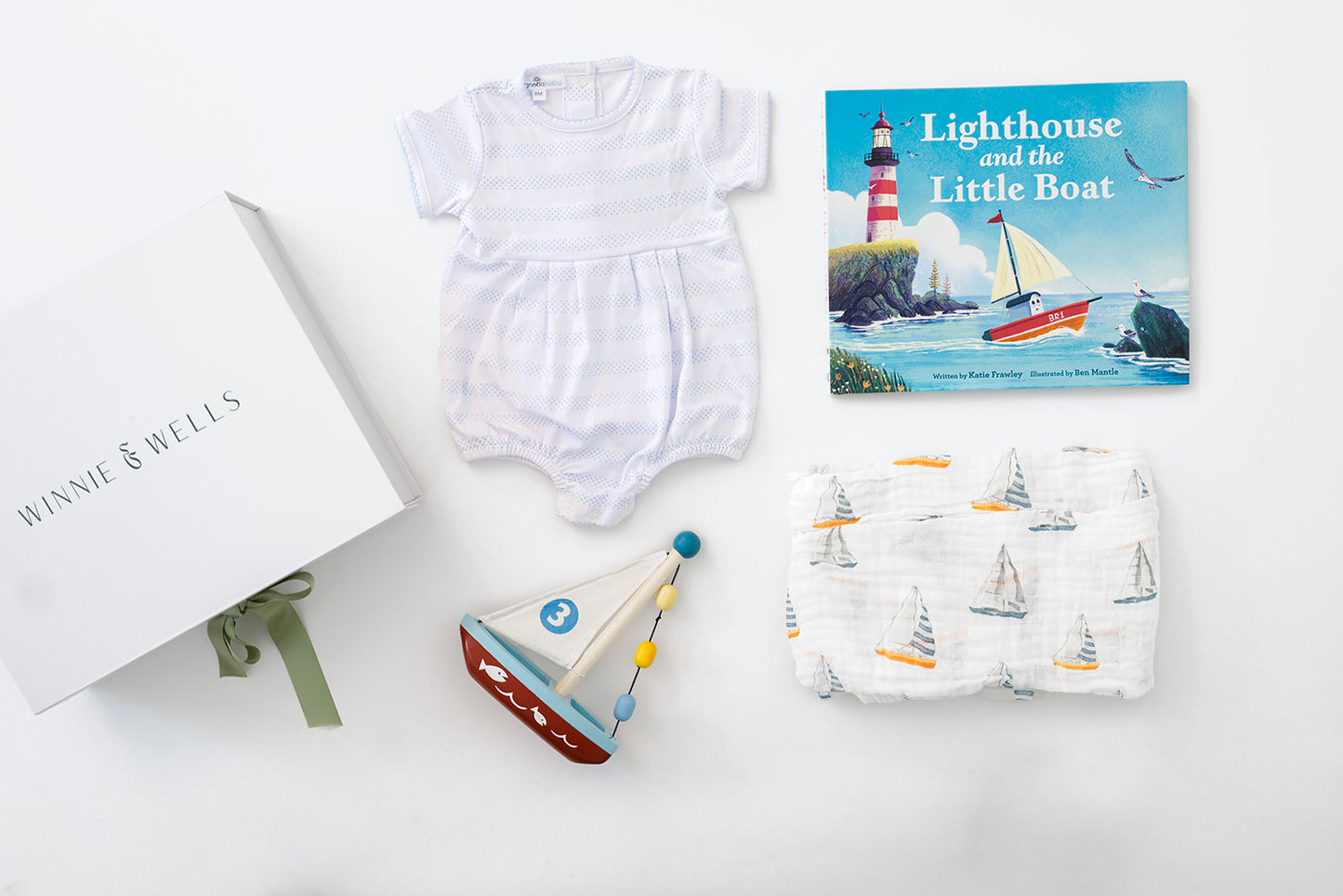 Decorative image of blue and white striped baby onesie, sail boat print swaddle blanket, wooden sailboat toy, and picture book