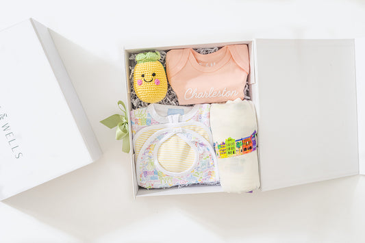 Baby gift set with clothes and toys in a box on a white background