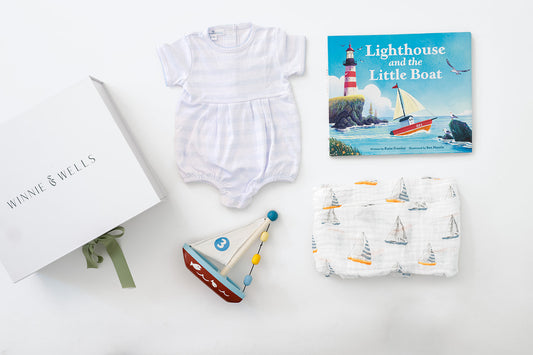 Decorative image of blue and white striped baby onesie, sail boat print swaddle blanket, wooden sailboat toy, and picture book