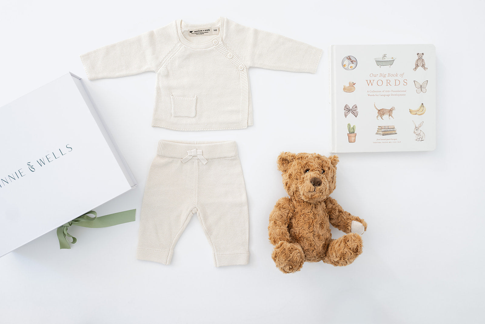 decorative image lay out with teddy bear, first words book and cream knit set 